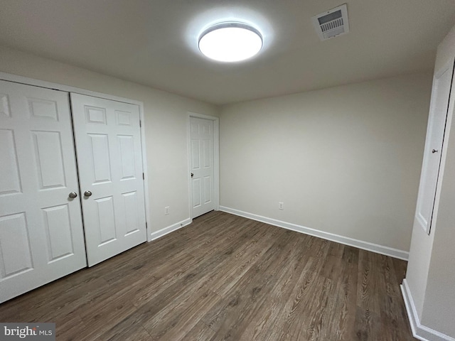 unfurnished bedroom featuring dark hardwood / wood-style flooring and a closet