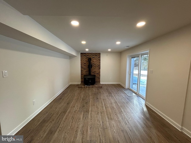 unfurnished living room with dark wood-type flooring and a wood stove