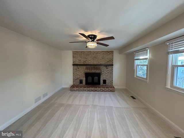 unfurnished living room with light carpet, ceiling fan, and a fireplace