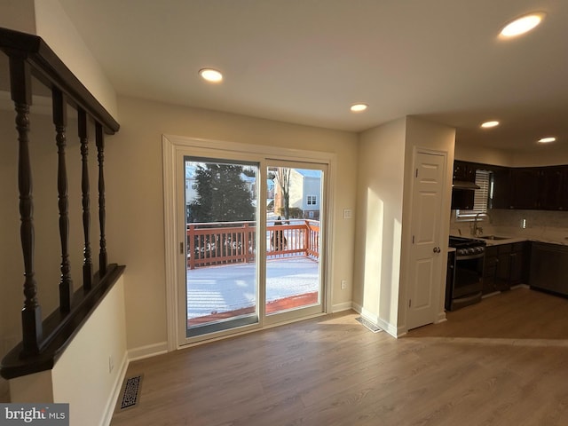 doorway to outside featuring light hardwood / wood-style floors and sink