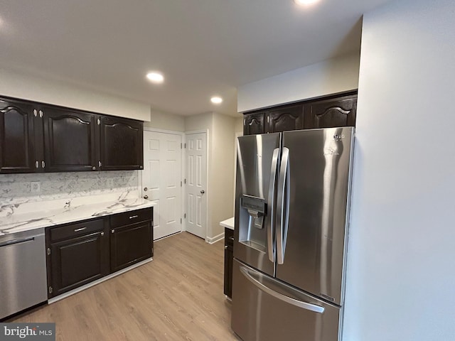 kitchen with appliances with stainless steel finishes, light hardwood / wood-style flooring, and tasteful backsplash