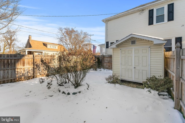 yard layered in snow featuring a storage shed