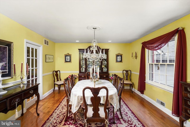 dining space with a chandelier, visible vents, and hardwood / wood-style flooring