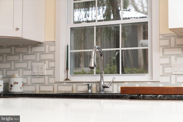 details with dark stone counters, white cabinets, and decorative backsplash