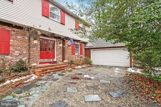 view of front of house featuring driveway, brick siding, and an attached garage