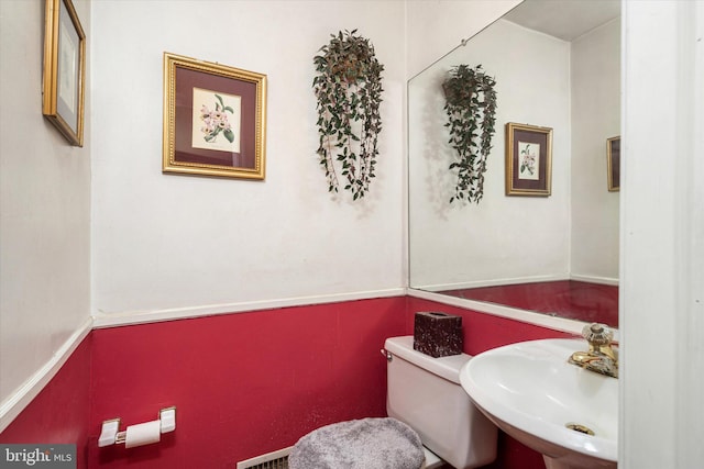 half bathroom with visible vents, a sink, and toilet