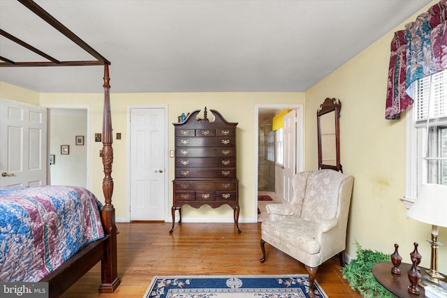 bedroom with ensuite bath, baseboards, and wood finished floors