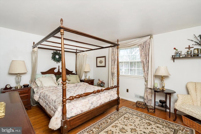 bedroom featuring baseboards, visible vents, and wood finished floors