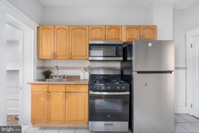 kitchen featuring light tile patterned floors, backsplash, appliances with stainless steel finishes, and sink