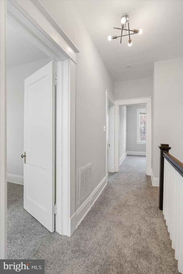 hallway featuring light carpet and a chandelier