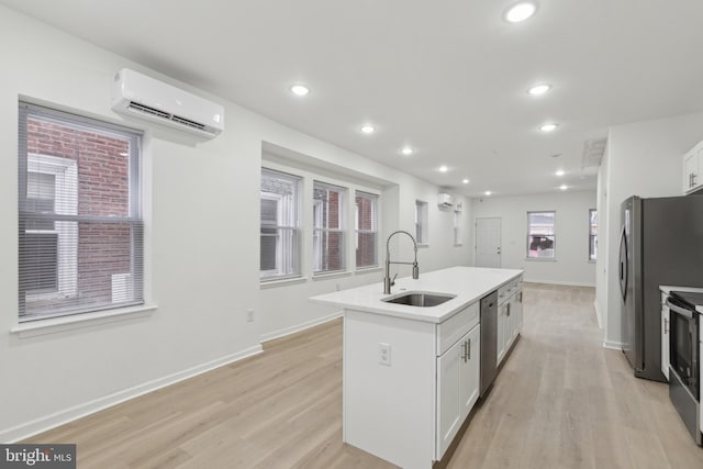 kitchen featuring a center island with sink, white cabinets, a wall mounted air conditioner, and stainless steel appliances