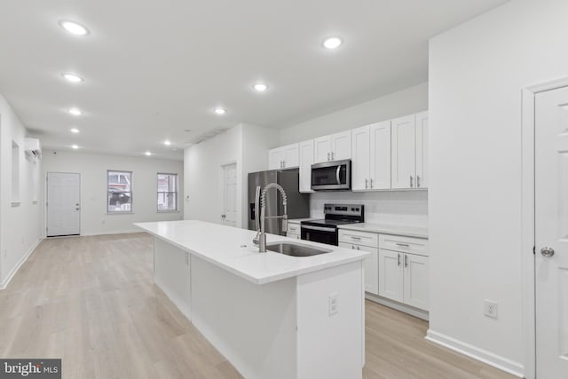 kitchen featuring sink, white cabinets, appliances with stainless steel finishes, and a kitchen island with sink