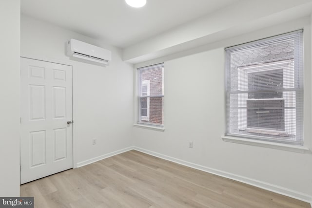 empty room with light wood-type flooring and an AC wall unit