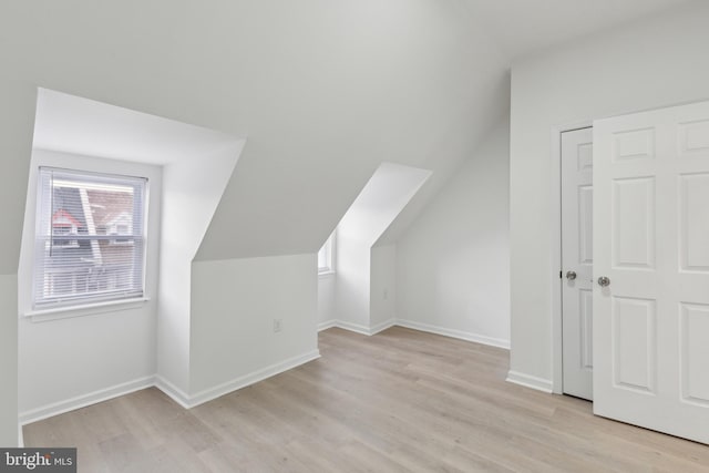 bonus room with lofted ceiling and light wood-type flooring