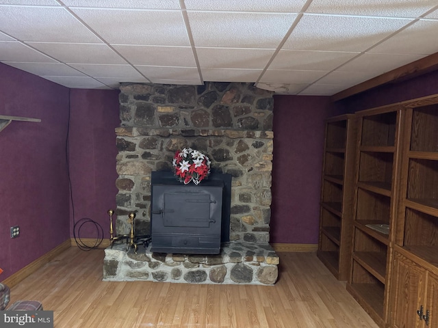 interior space with a paneled ceiling, a wood stove, and hardwood / wood-style flooring