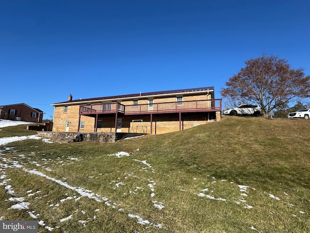 snow covered rear of property featuring a deck and a lawn