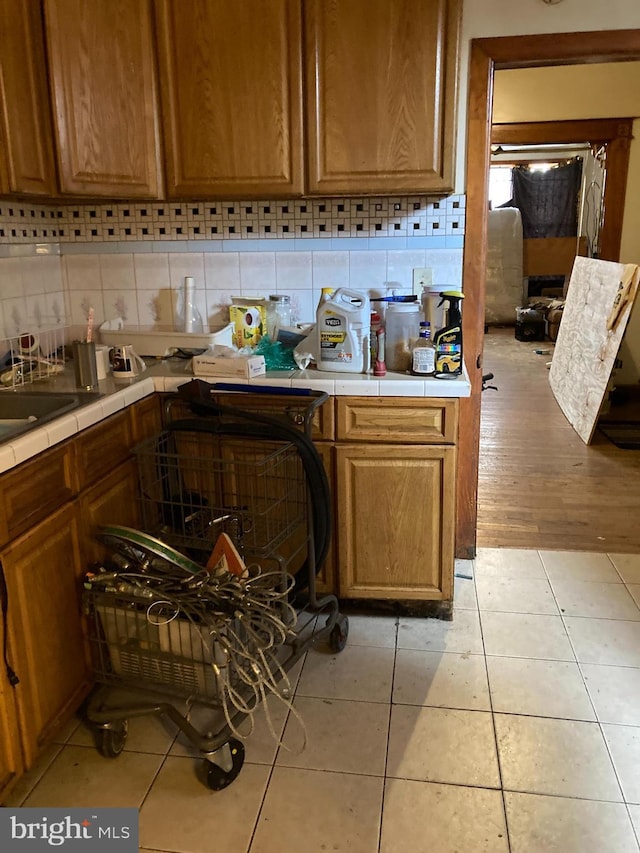 kitchen with light tile patterned floors, tile counters, and tasteful backsplash