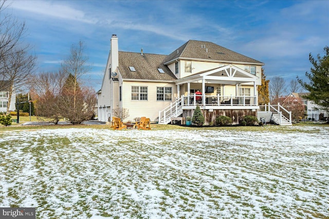 snow covered house with a garage and covered porch