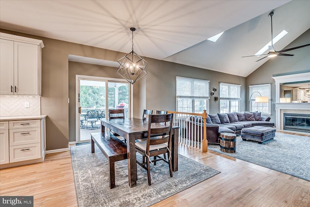 dining room featuring ceiling fan with notable chandelier, light hardwood / wood-style flooring, and lofted ceiling