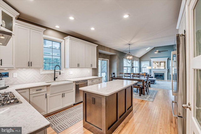 kitchen featuring appliances with stainless steel finishes, white cabinets, pendant lighting, a healthy amount of sunlight, and lofted ceiling