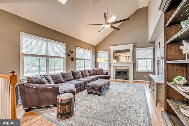 living room with ceiling fan, high vaulted ceiling, and light hardwood / wood-style flooring