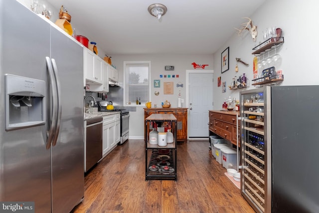 kitchen with dark hardwood / wood-style flooring, stainless steel appliances, beverage cooler, and white cabinets