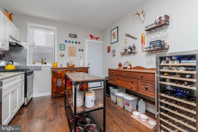 kitchen with dishwashing machine, white cabinetry, dark hardwood / wood-style flooring, gas range, and beverage cooler