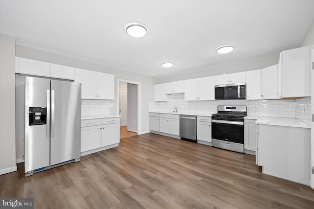 kitchen featuring stainless steel appliances, white cabinets, tasteful backsplash, and dark wood-type flooring