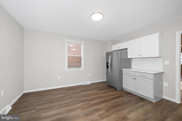 kitchen with dark hardwood / wood-style flooring, stainless steel fridge with ice dispenser, decorative backsplash, and white cabinetry
