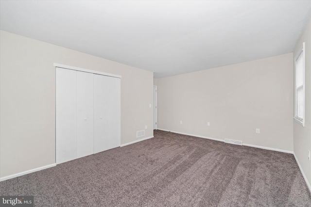 unfurnished bedroom featuring dark carpet and a closet