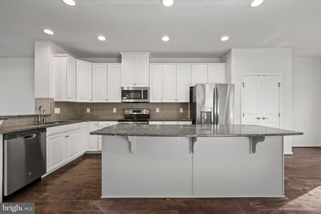 kitchen with dark stone counters, stainless steel appliances, and white cabinetry