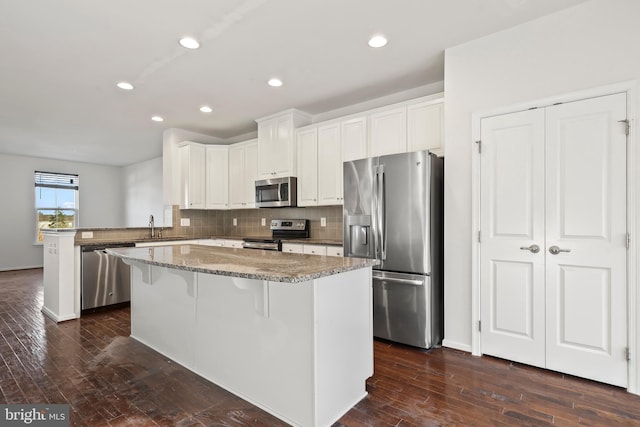 kitchen featuring appliances with stainless steel finishes, light stone countertops, kitchen peninsula, white cabinets, and sink