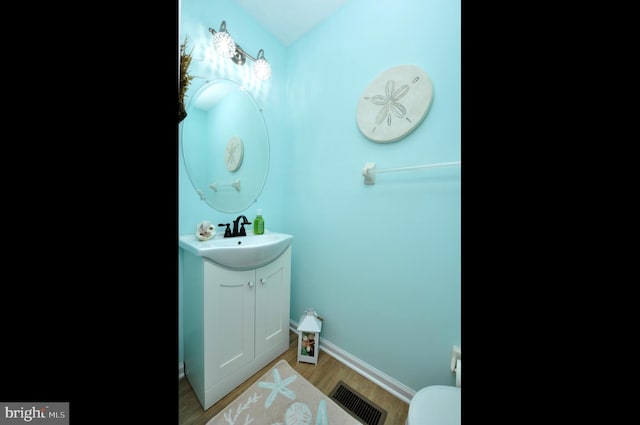 bathroom featuring toilet, wood-type flooring, and vanity