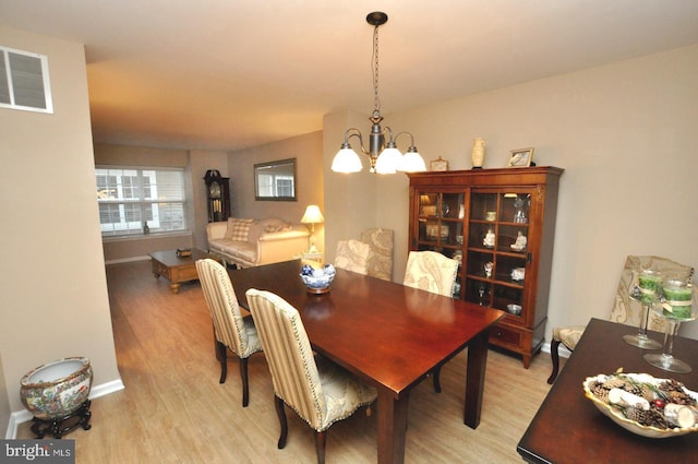 dining space with light wood-type flooring and an inviting chandelier