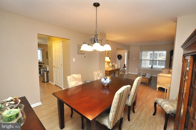 dining area with light hardwood / wood-style floors and a notable chandelier