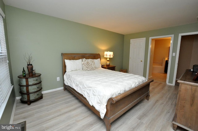 bedroom featuring light wood-type flooring and connected bathroom