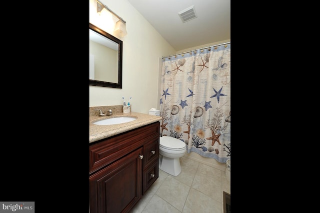 bathroom with toilet, vanity, and tile patterned floors