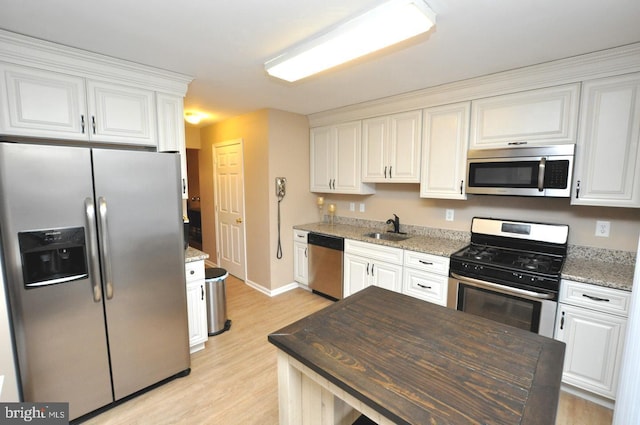 kitchen with white cabinets, dark stone counters, appliances with stainless steel finishes, and sink