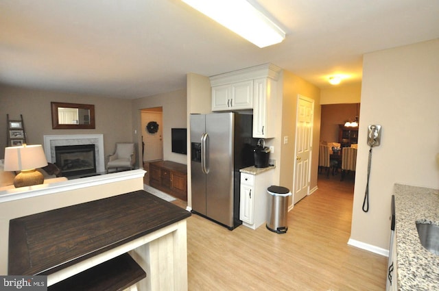 kitchen featuring light hardwood / wood-style floors, a notable chandelier, stainless steel fridge, light stone counters, and white cabinets