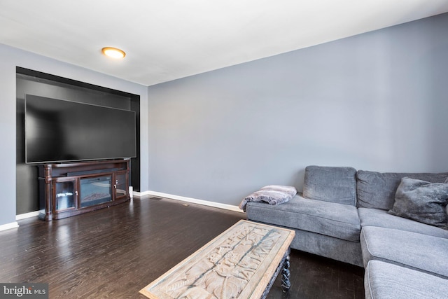 living room with dark wood-type flooring and a fireplace