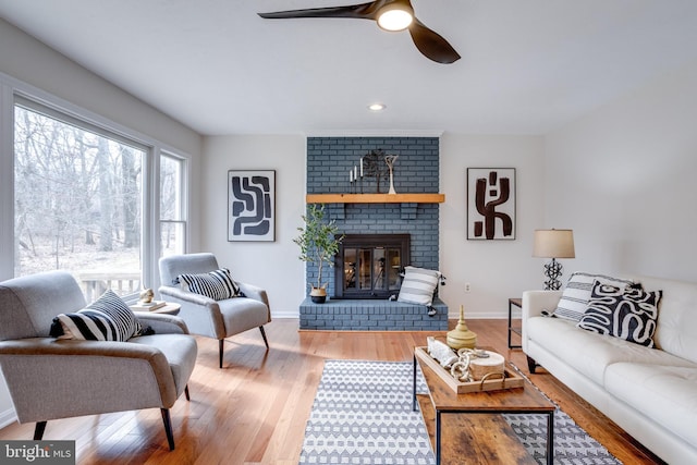 living area with recessed lighting, a brick fireplace, ceiling fan, wood finished floors, and baseboards