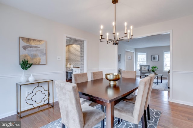 dining area featuring an inviting chandelier, baseboards, and wood finished floors