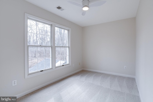 carpeted spare room featuring visible vents, ceiling fan, and baseboards