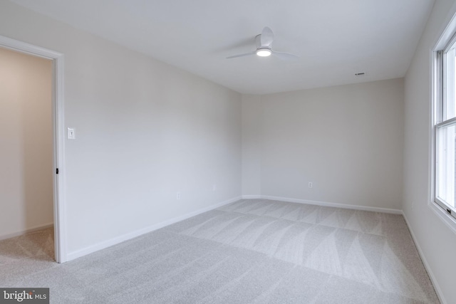 empty room featuring baseboards, a ceiling fan, and light colored carpet