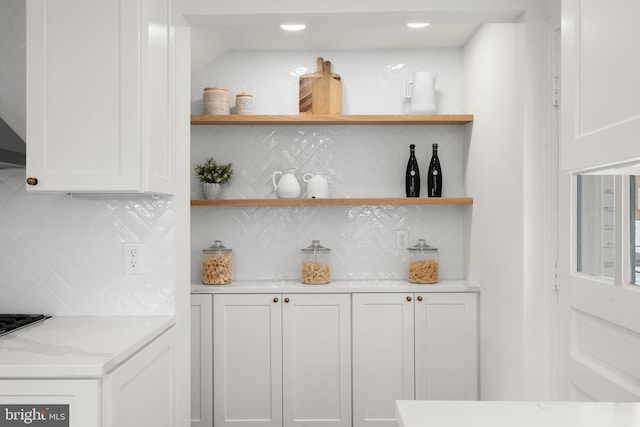 bar with light stone counters, white cabinets, gas stovetop, and decorative backsplash