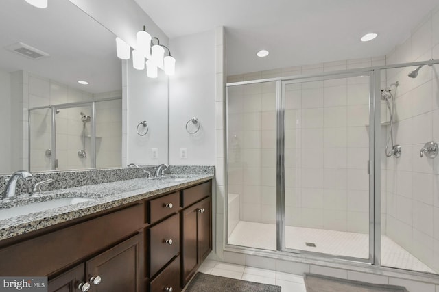 bathroom featuring tile patterned flooring, a shower with shower door, and vanity