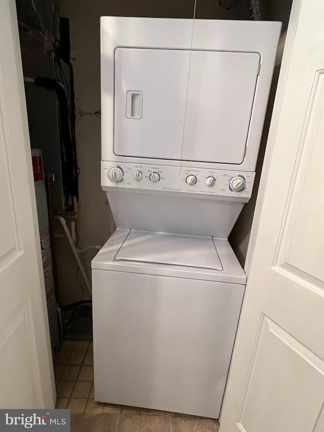 clothes washing area featuring light tile patterned floors, gas water heater, and stacked washer and dryer