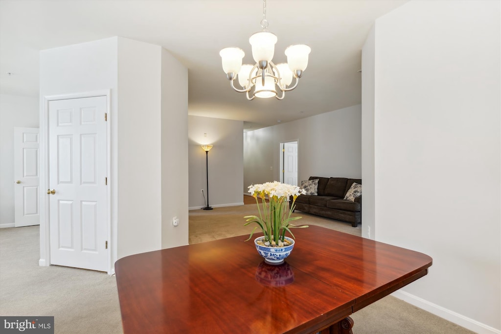 dining space featuring baseboards, a chandelier, and light colored carpet