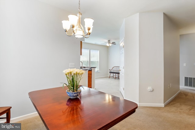 dining space with light carpet, baseboards, visible vents, and ceiling fan with notable chandelier