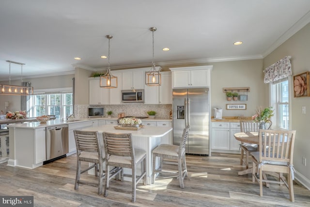 kitchen featuring appliances with stainless steel finishes, hanging light fixtures, white cabinets, and a kitchen island